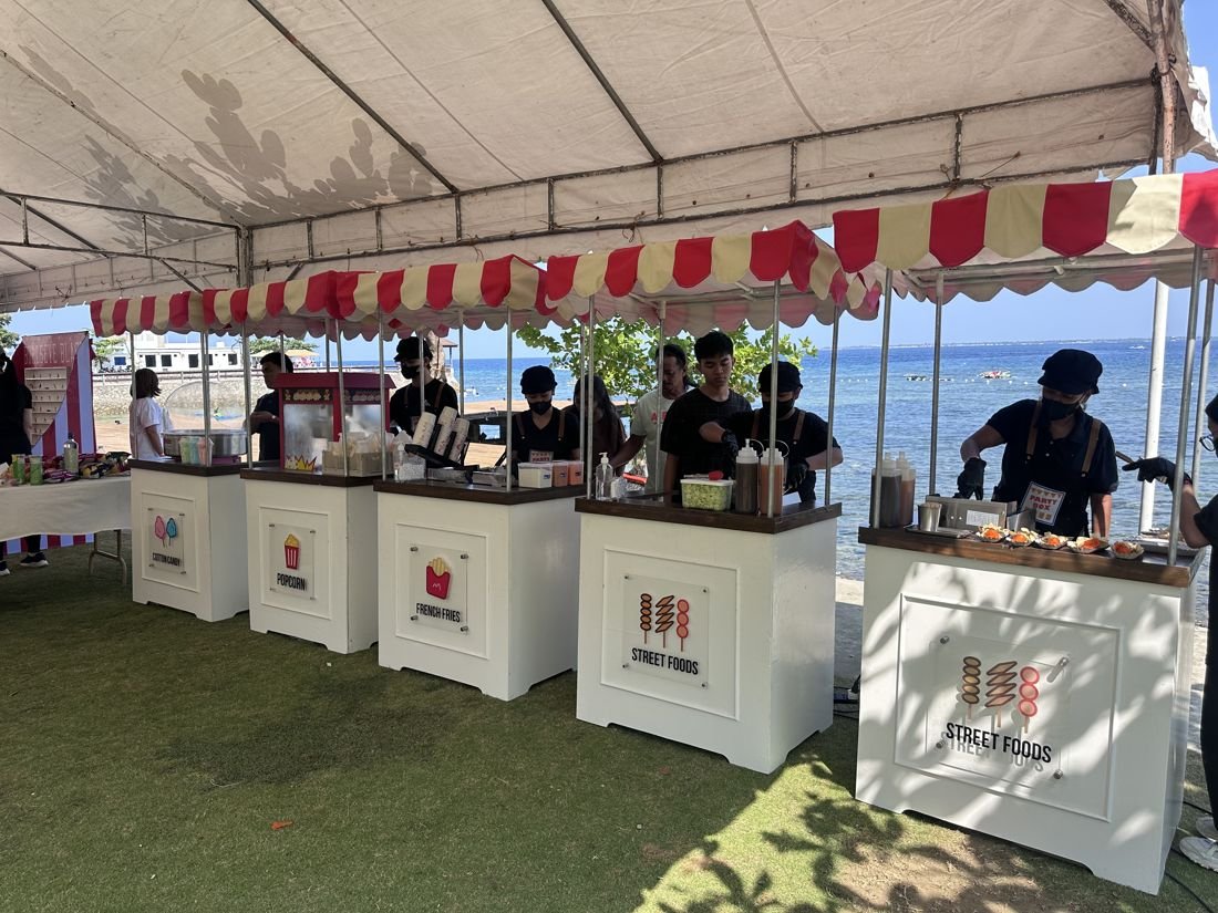 Five PartyBox carts under a seaside tent with crew serving guests
