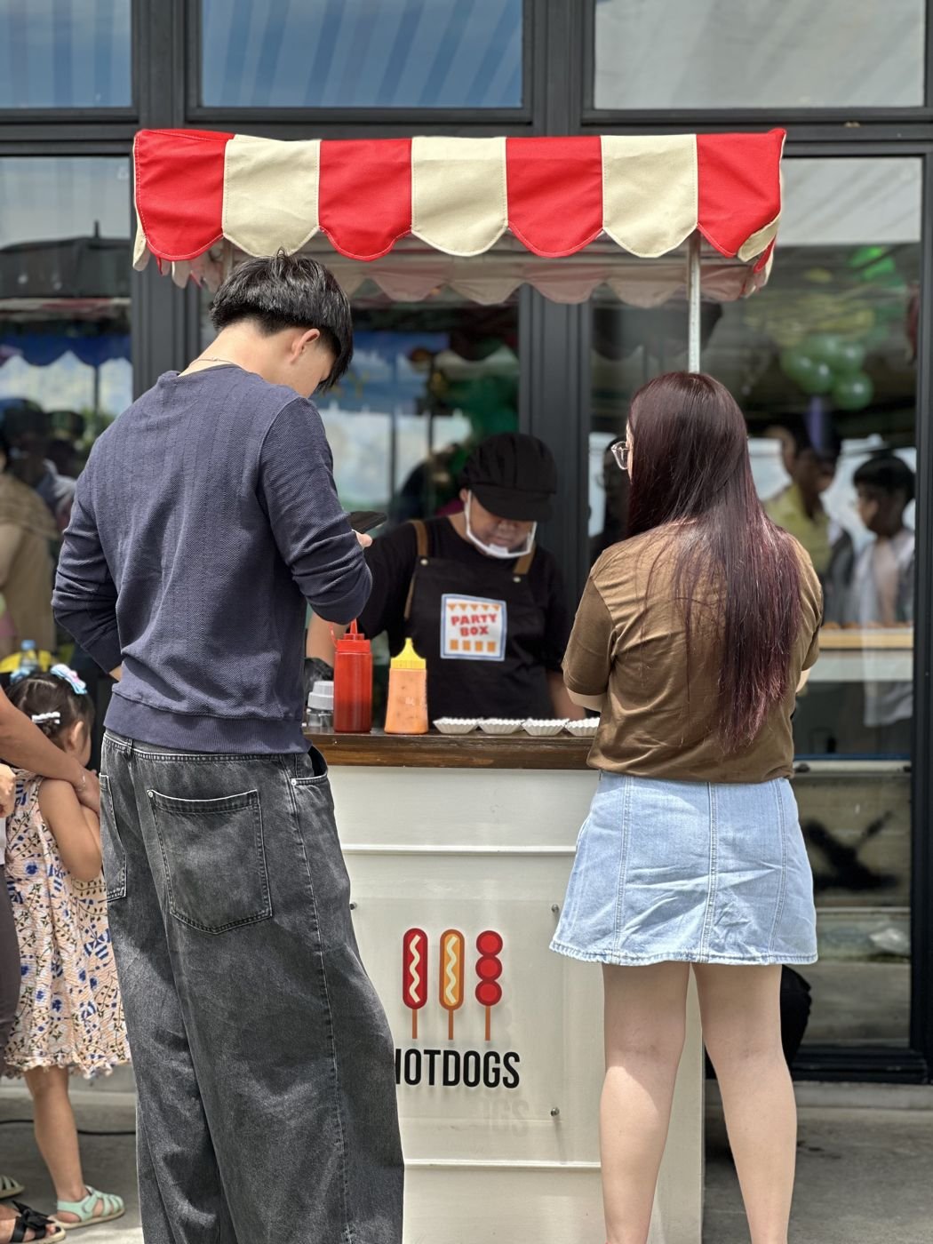 Crew serving a guest at the hotdog cart